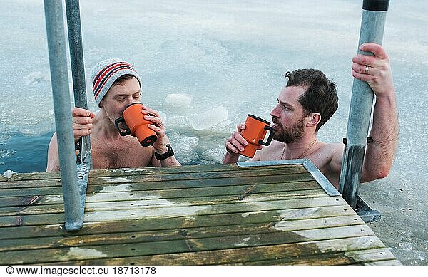 two friends drinking hot drink whilst cold water swimming