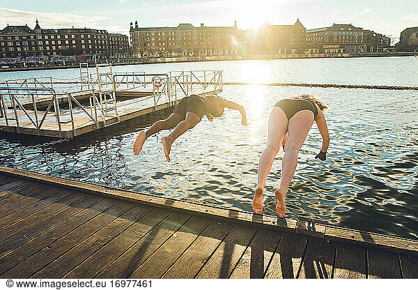 Two Friends of Different Age and Race Jumping in Cold Water in Denmark
