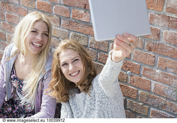 Two friends taking selfie with her digital tablet  Munich  Bavaria  Germany