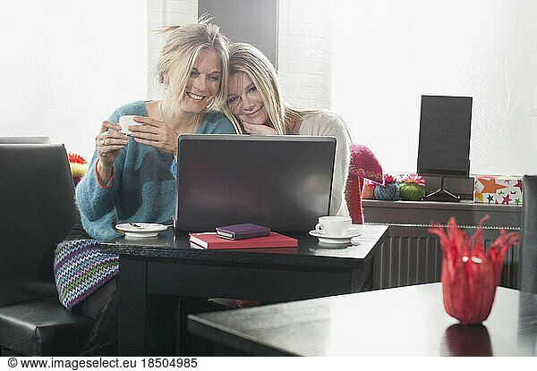 Two friends using laptop and drinking coffee in coffee shop  Bavaria  Germany