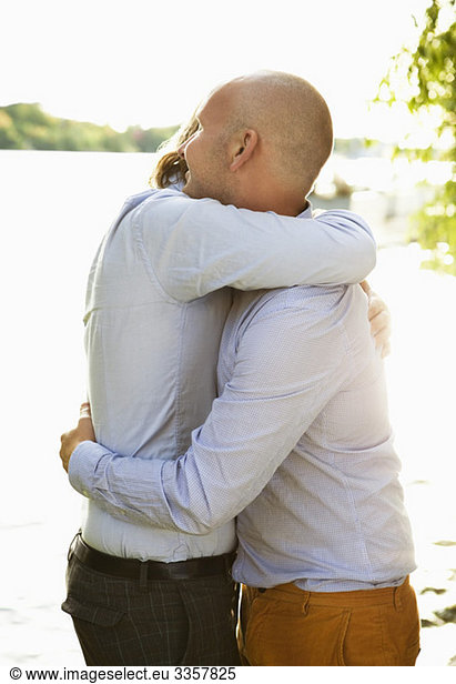 Two gay men hugging by the water's edge