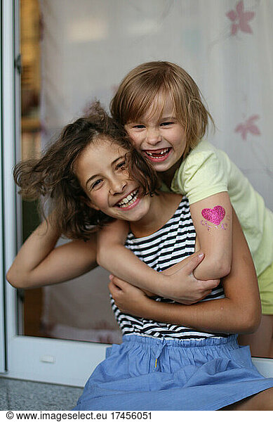 Two girls hug and laugh close-up.