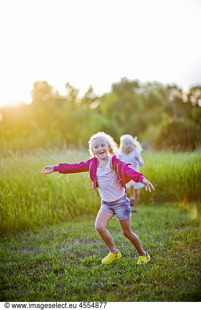 Two girls running through field