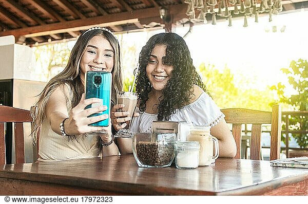 Two girls taking a selfie and drinking coffee  two girls friends in a coffee shop taking a selfie