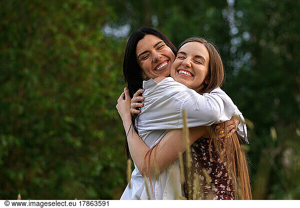 Two Girls with Long Hair Hugging Each Other and Laughing
