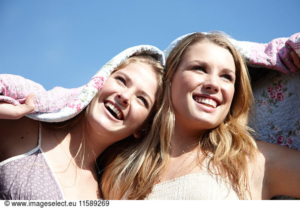 Two girls wrapped in a blanket outdoors