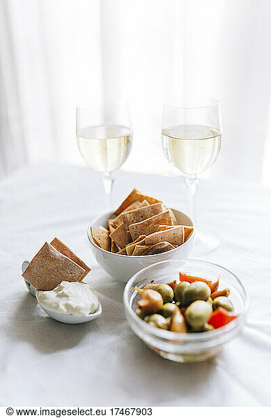 Two glasses of white wine and bowl of crackers with dipping sauce