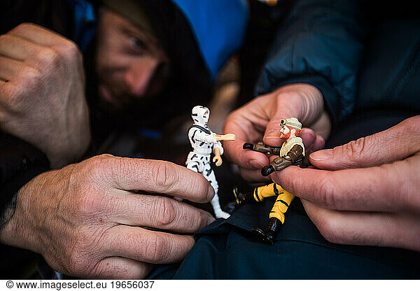 Two grown men hold their look-a-like action figures