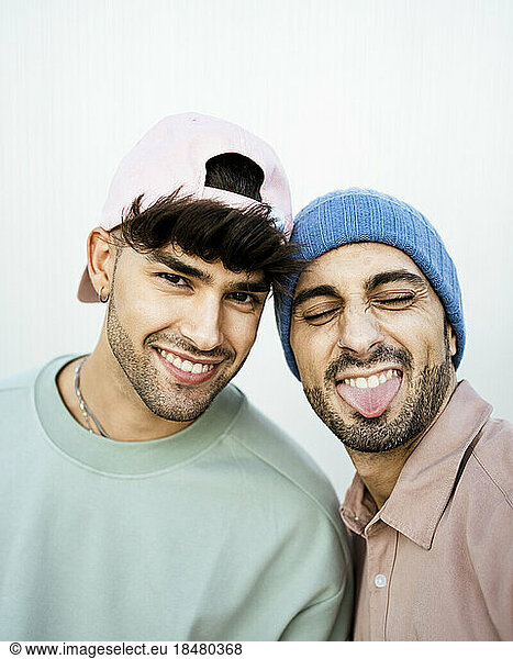 Two happy men wearing hat and cap against white background