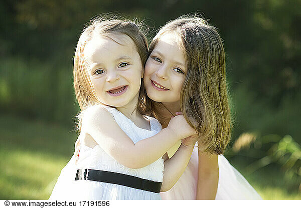 Two happy sweet little girls in Easter dresses outdoors.