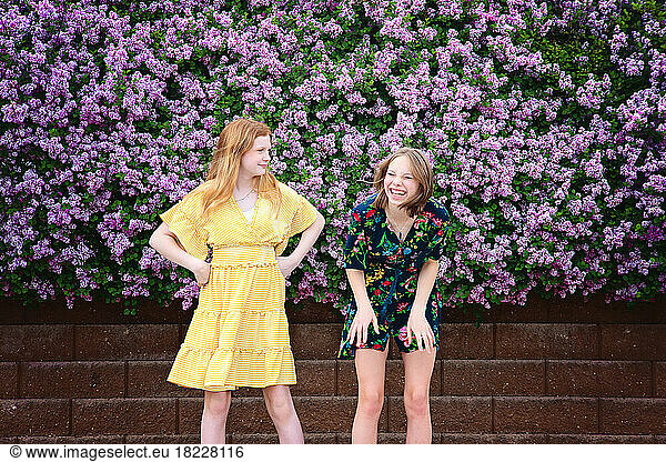 Two happy teen girls laughing and surrounded by lilacs.