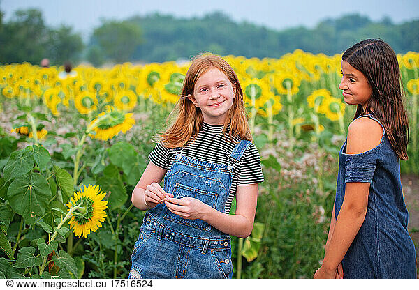 Two happy tween girls in a sunflower field.