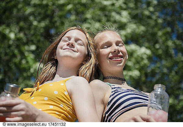 Two happy tween girls in swimsuits outdoors.