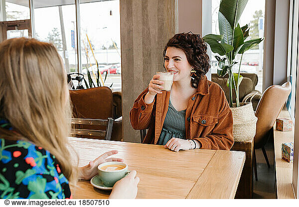 Two happy women meeting up for coffee inside