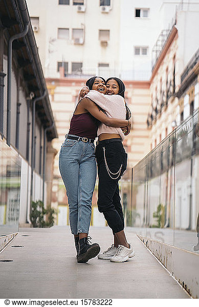 Two happy young women hugging in the city