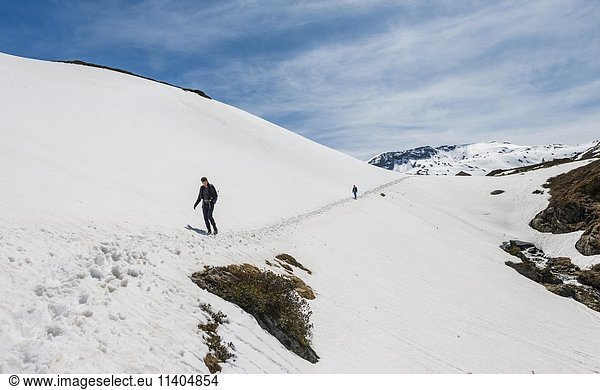 Two hikers crossing snowfield  mountains  Rohrmoos Obertal  Schladming Tauern  Schladming  Styria  Austria  Europe