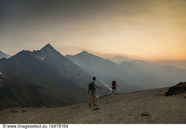 Two hikers walk on a trail towards the summit of Glacier Peak  WA.