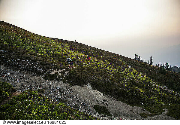Two hikers walk on a trail towards the summit of Glacier Peak  WA.
