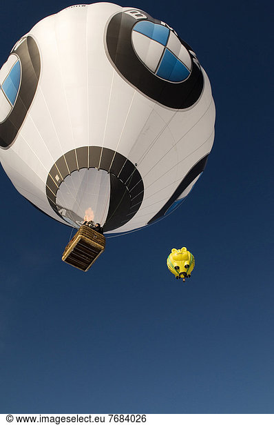 Two hot air balloons up in the sky  one with BMW logos and a yellow balloon in the shape of a smiling pig 12th balloon festival of Tegernsee  Montgolfiade  Bad Wiessee  Tegernsee  Bavaria  Germany  Europe