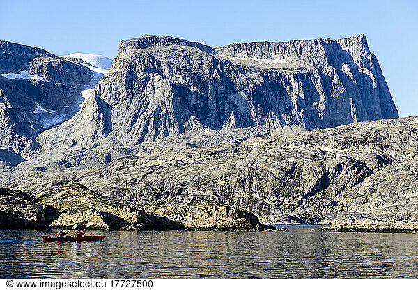 Two kayakers on the water off the rocky shore  Greenland.