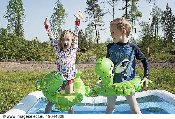 two kids in a paddling pool dancing and laughing