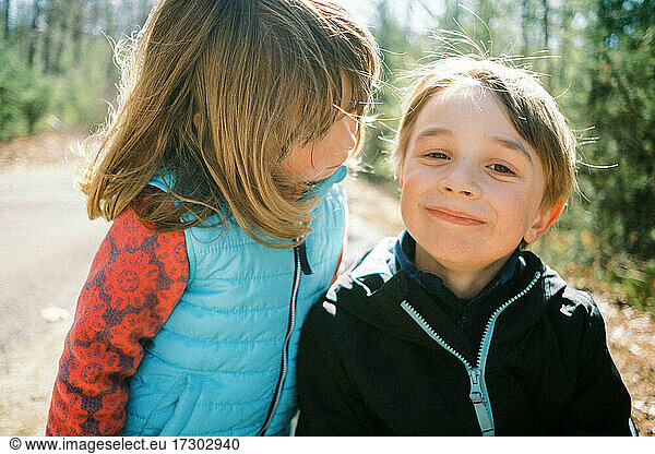 Two kids outside in the sun playing together during a hike in nature