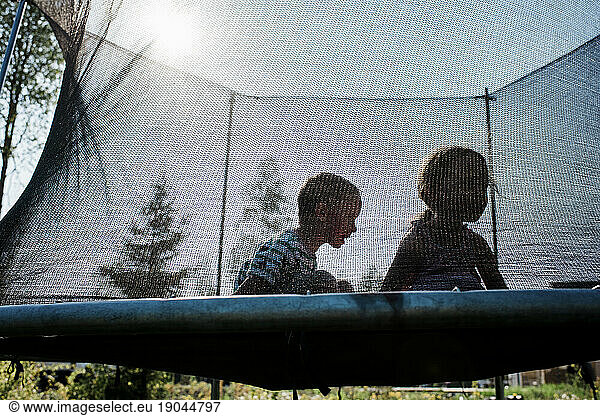 two kids playing on a trampoline having fun