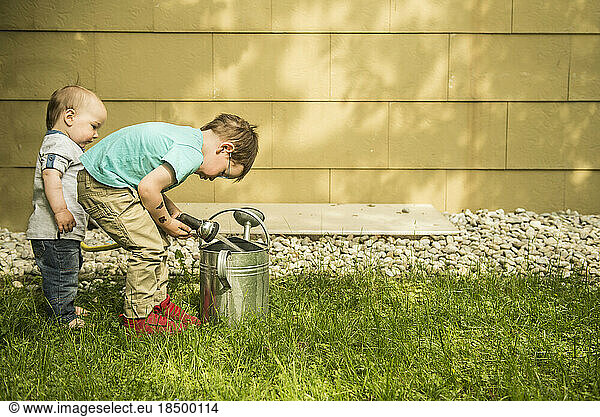 Two little boys in the garden filling watering can
