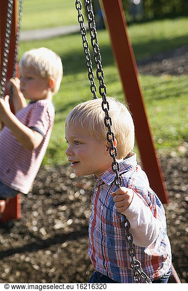 Two little boys ( 2-3) (4-5) sitting on swing