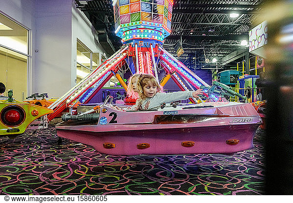 two little girls on indoor amusement park ride having fun