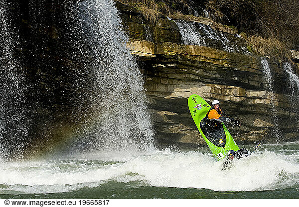 Two male kayakers paddling around waterfalls in a two person kayak.