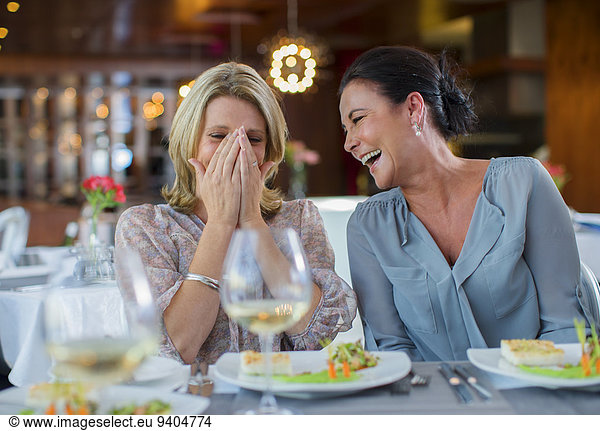 Two mature women laughing in restaurant