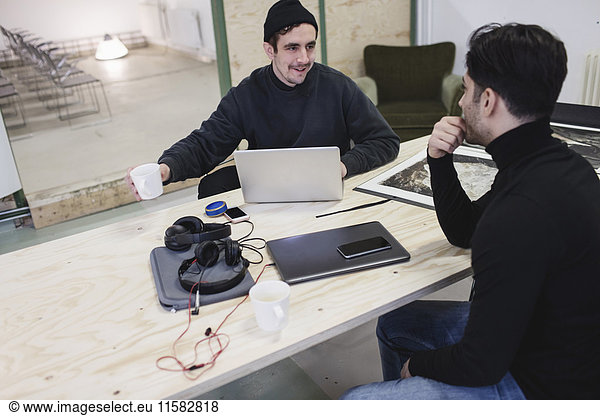 Two men discussing at desk in creative office