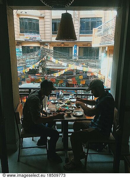 Two men eating lunch overlooking city streets in Asia