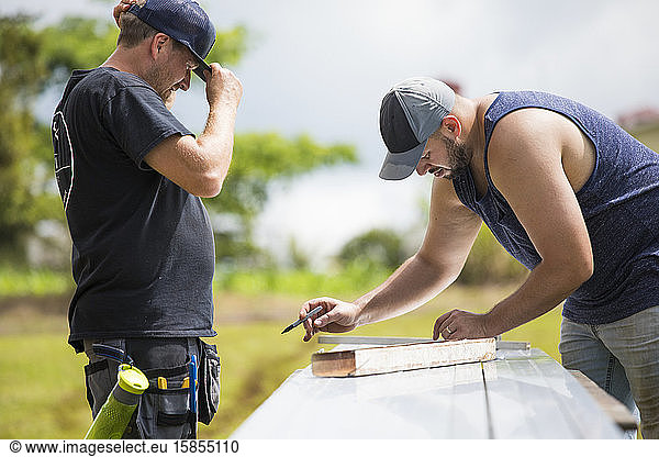 Two men measuring brackets for solar panel installation.