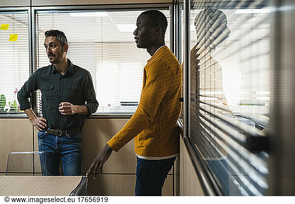 Two men of different ethnicities working in meeting room.