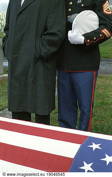 Two men paying respects at an outdoor grave site.