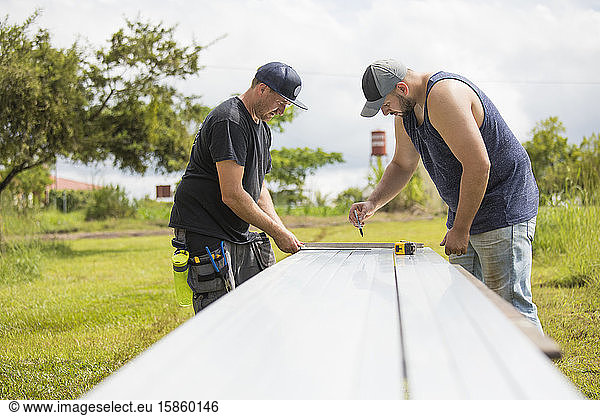 Two men preparing steel excursion for solar panel installation.