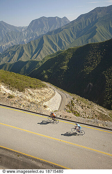 Two men riding his bike on a road of a mountainous landscape. Queretaro  Mexico.