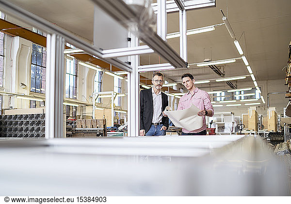 Two men with plan in a factory
