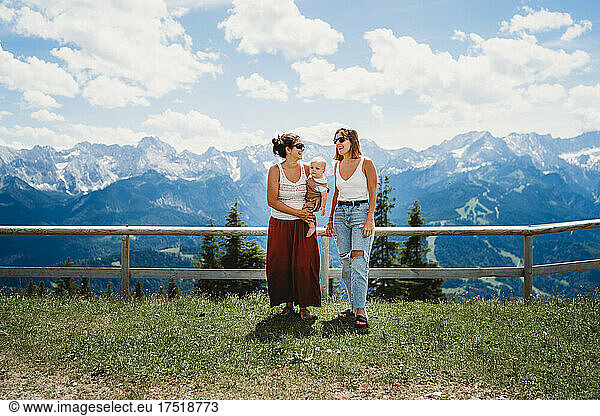 Two moms and baby smiling in the mountains in summer