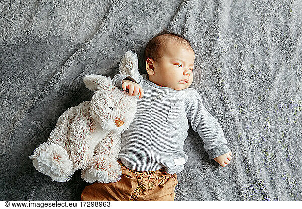 Two months newborn Asian baby boy lying on bed with rabbit comfort toy