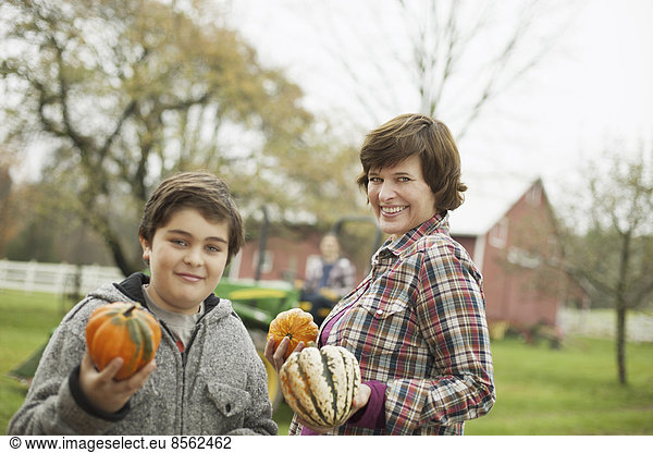 Two people  a woman and a child on an organic farm  carrying harvested vegetables  squashes and pumpkins. Organic farming.