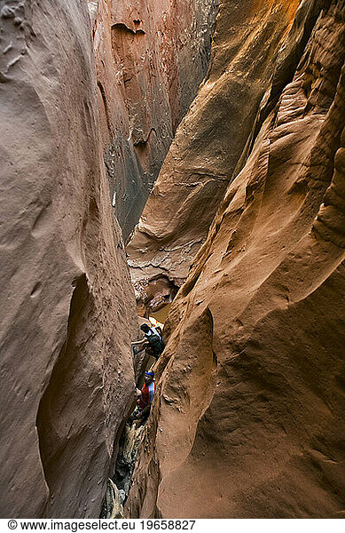Two people canyoneering in slot canyon  Utah.