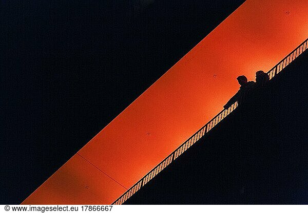Two people  couple standing on observation deck Plaza  enjoying view  silhouettes in the darkness  illuminated orange  Elbe Philharmonic Hall in the evening  view from below  text free space  Hamburg  Germany  Europe