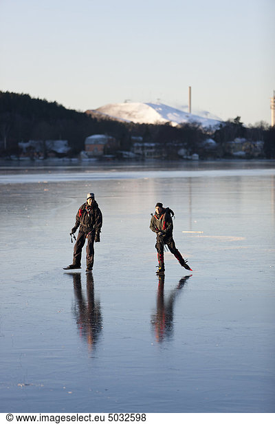 Two people ice skating on frozen lake