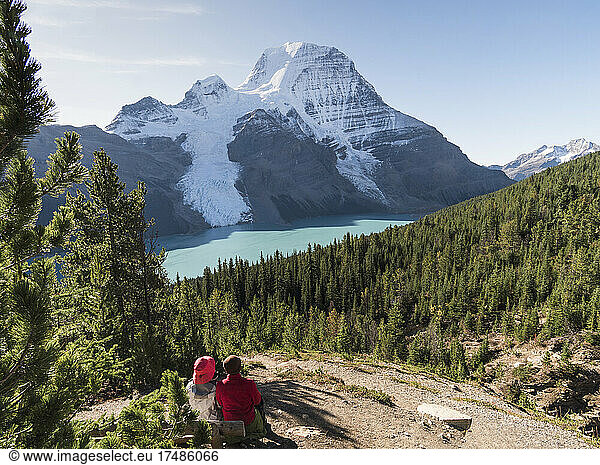 Two people resting by a hiking path  view of Mount Robson and the Rockies.