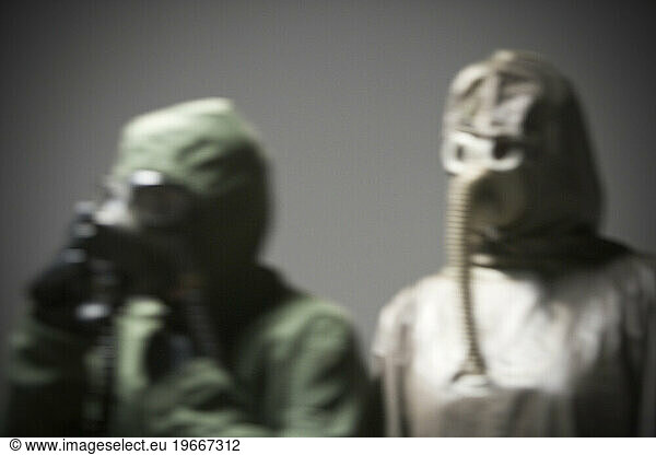 Two people wearing protective clothing and gas masks.