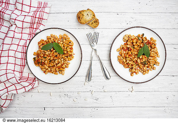 Two plates of Italian baked beans (fagioli alluccelletto) with tomatoes and sage
