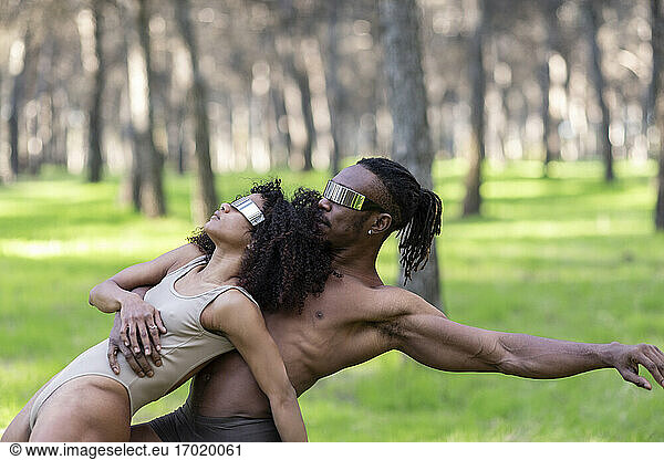 Two professional dancers wearing futuristic goggles performing in middle of forest